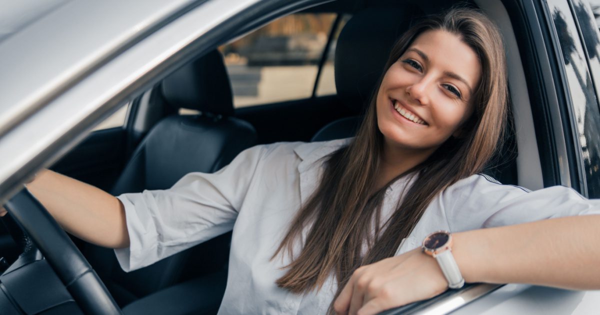 Woman smiling while driving know she has affordable car insurance