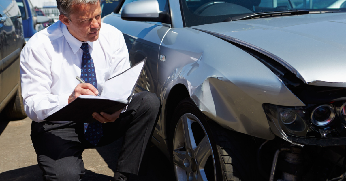 Insurance adjuster inspecting salvage car