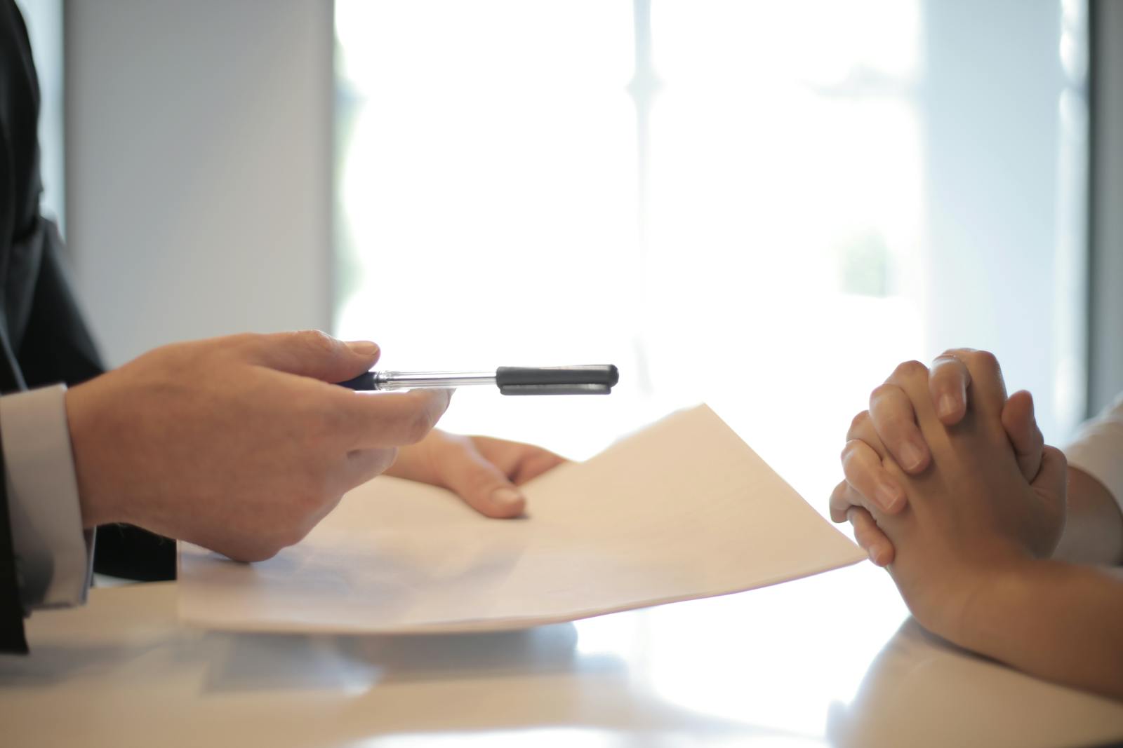 Crop businessman giving contract to woman to sign