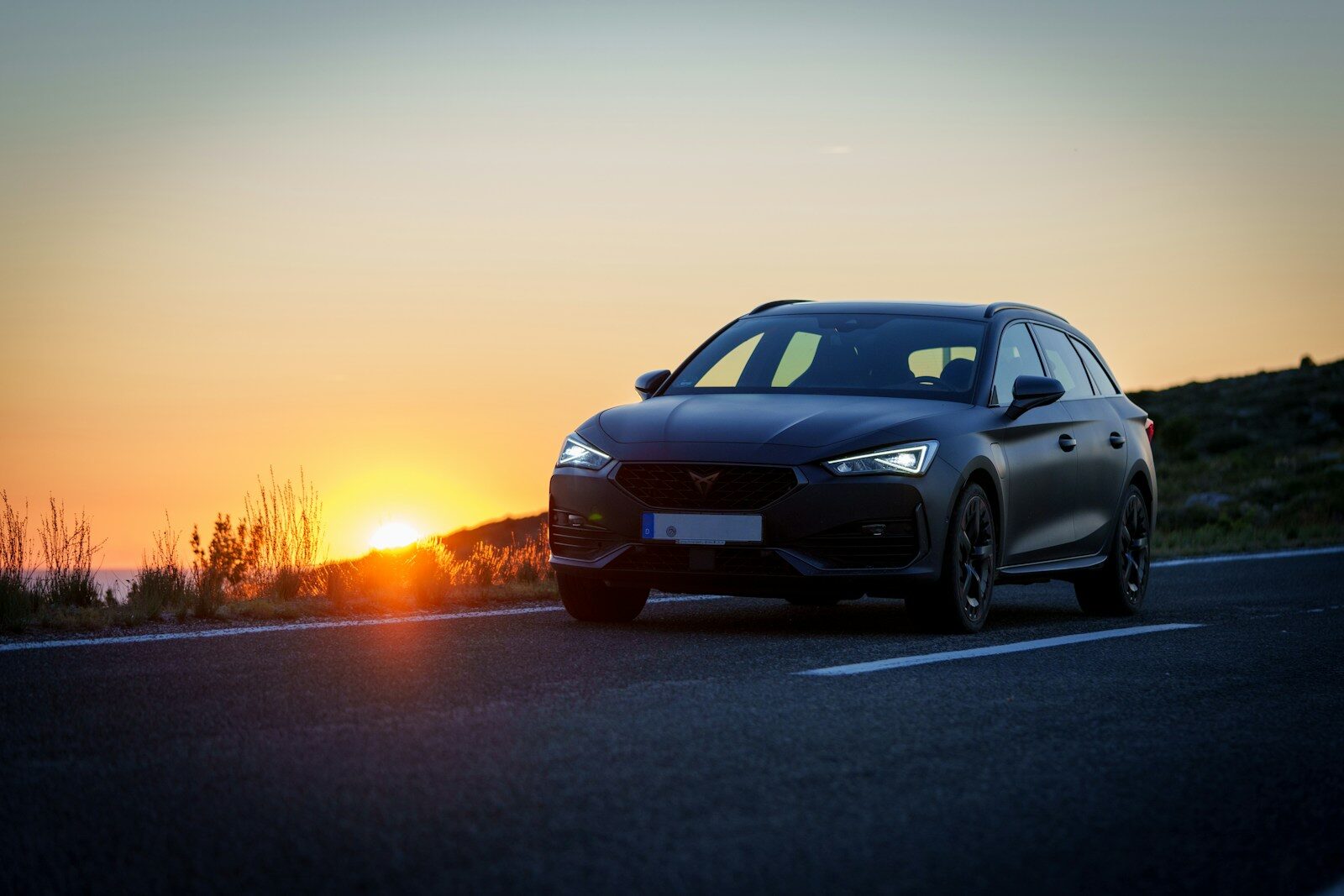 A car driving down a road at sunset